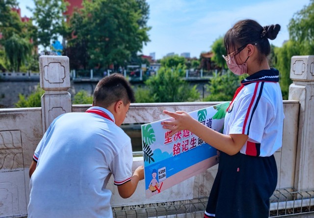 徐水小学学雷锋志愿者在瀑河河边张贴防溺水警示标语。 徐水区委宣传部供图