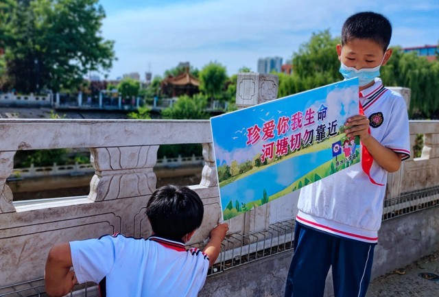 徐水小学学雷锋志愿者在瀑河河边张贴防溺水警示标语。 徐水区委宣传部供图